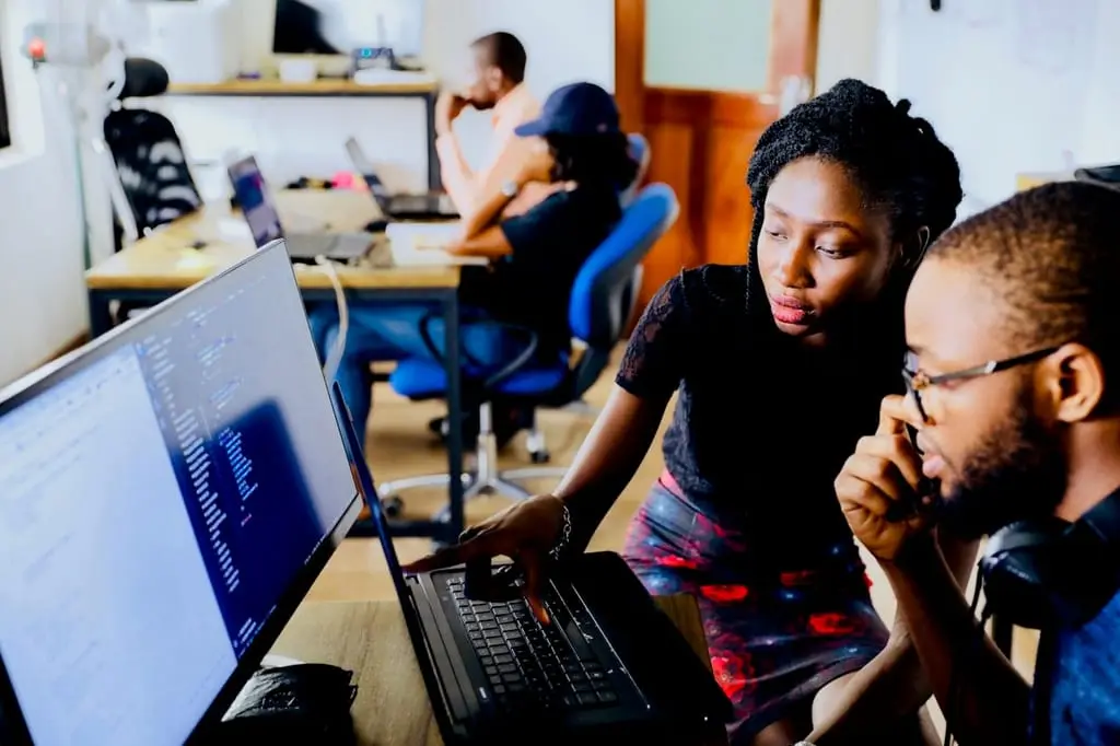 Two colleagues reviewing work together at a shared workstation
